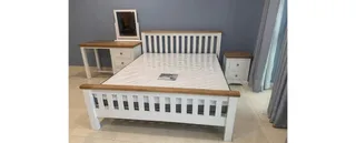 White wooden bed with bedside tables and a dressing table.
