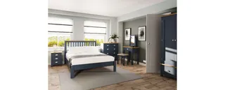 Dark blue wooden bed, wardrobes, dressers and desk in a bedroom.