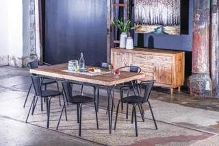 Wooden dining table and black metal chairs beside a wooden sideboard