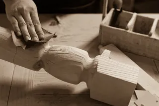 Worker sanding a carved wooden furniture component