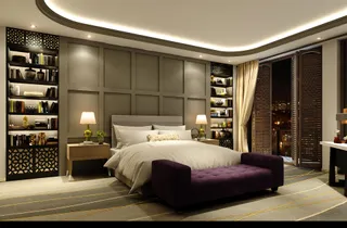 Finished hotel-style bedroom with bed, upholstered bench and built-in shelving