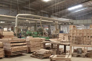 Furniture factory floor with timber stacks, machinery and assembled wood parts