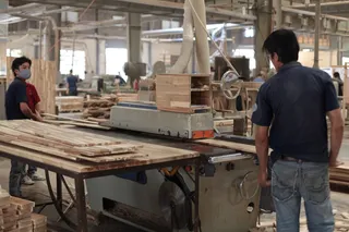 Workers operating woodworking machinery on timber panels
