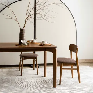 Wooden dining table and chairs styled with tableware in a bright room