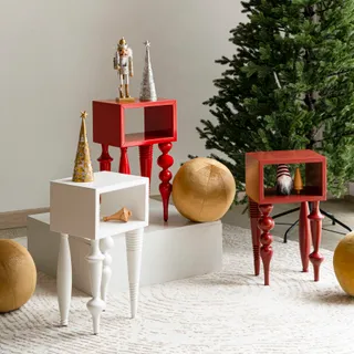 Red and white decorative side tables displayed beside a Christmas tree