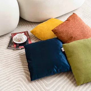 Four colorful fabric cushions arranged on a patterned rug