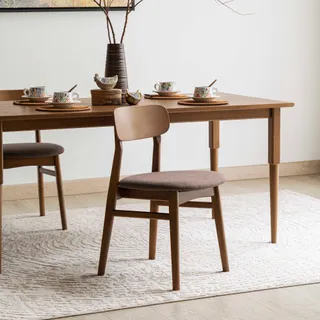 Wooden dining table and upholstered chairs arranged in a bright interior