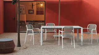 White table and woven chairs arranged in a red-walled outdoor dining area