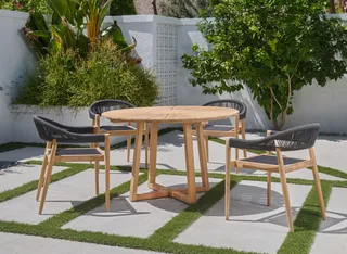 Round wooden outdoor table with three dark woven chairs