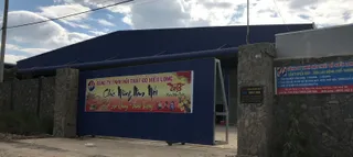 Exterior entrance of Hieu Long Furniture's factory with blue gate and company sign.