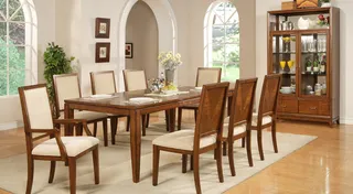 Wood dining table with upholstered chairs and matching glass-front cabinet.