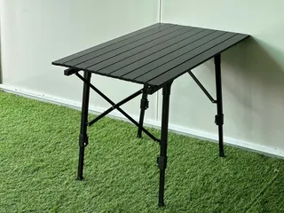 Black folding slatted outdoor camping table on artificial grass