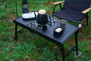Black folding camping table with camping cookware and chair