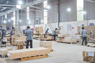 Workers processing timber and assembling furniture in a factory workshop