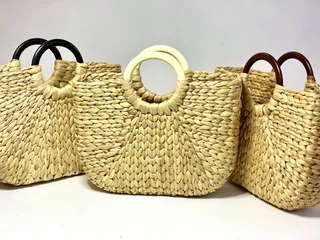Three natural-fiber woven handbags with contrasting round handles