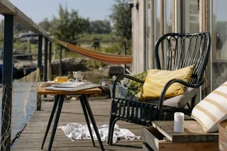 Black woven outdoor chair beside a wooden table on a deck