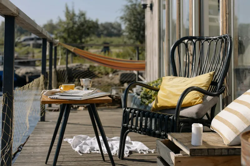 Black woven outdoor chair beside a wooden table on a deck