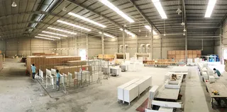 Large furniture factory floor with workers, machinery and assembled furniture