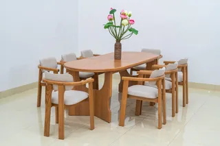 Light wooden dining table surrounded by upholstered armchairs