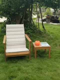 Cushioned wooden lounge chair and side table in a garden