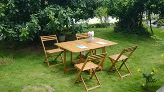 Wooden folding table and four chairs arranged on a grassy garden