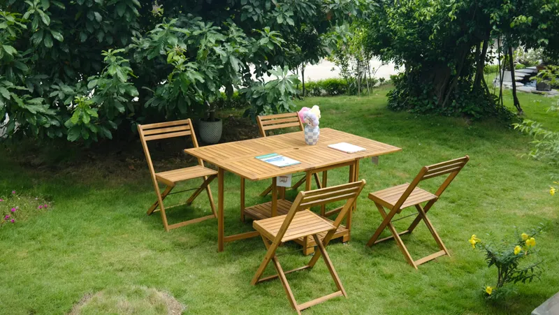 Wooden folding table and four chairs arranged on a grassy garden