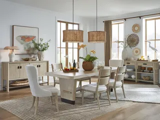 Light wood dining table and chairs with sideboard in a bright dining room.