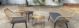 Woven outdoor lounge chairs, sofa and round coffee table in a courtyard.