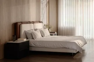 Bedroom with upholstered bed, wood wall paneling and dark bedside cabinet