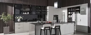 Bright fitted kitchen with island, white cabinets and dark wood wall panels