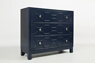 Dark navy three-drawer chest with geometric raised fronts and brass-colored knobs.