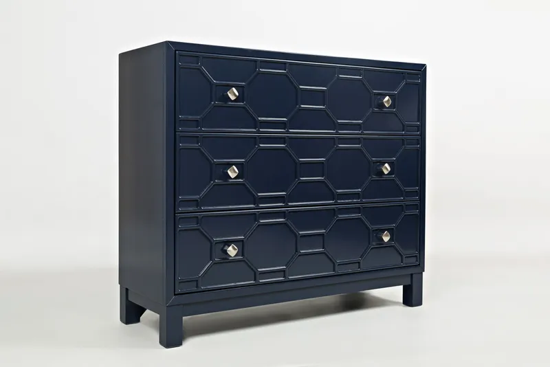 Dark navy three-drawer chest with geometric raised fronts and brass-colored knobs.