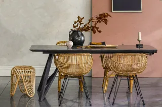 Rattan dining table with woven chairs and a matching stool