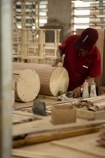 Furniture worker assembling a round wooden component at a workshop bench.