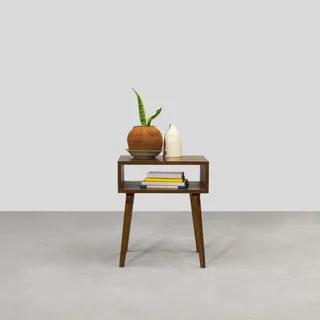 Wooden bedside table with open shelf, tapered legs and decorative vase.