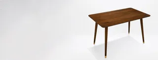Rectangular wooden dining table with tapered legs in a studio setting.