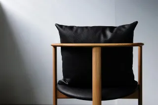 Black leather armchair with a rounded wooden frame and broad cushion.
