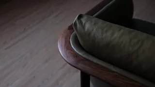 Close-up of a dark wood lounge chair with a curved leather back and armrest.