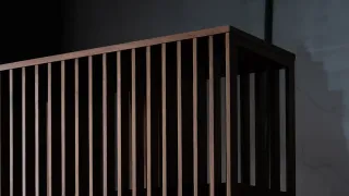 Dark wooden furniture piece with closely spaced vertical slats.