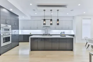 White kitchen with central island, integrated appliances and pendant lights