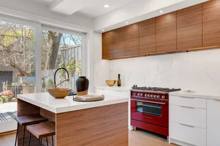 Kitchen with woodgrain upper cabinets, white island and red range cooker