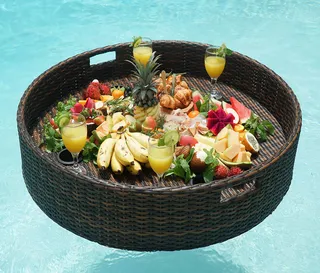 Round woven floating pool tray holding fruit and drinks