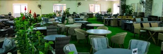 Furniture showroom displaying wicker chairs, round tables, sofas, and dining sets