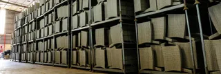 Warehouse aisle lined with racks of stacked wicker furniture
