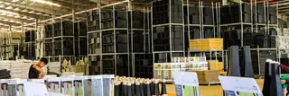 Furniture warehouse with stacked components, shelving, and a worker