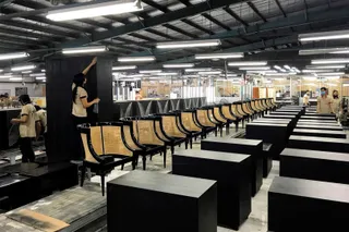 Rows of black tables and cane-backed chairs in the production hall