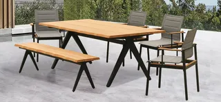 Outdoor wood dining table with matching bench and gray cushioned armchairs.