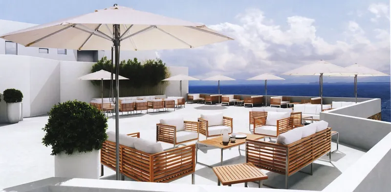 Outdoor wooden-slat lounge seating, tables and umbrellas on a seaside terrace.