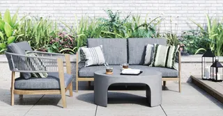 Outdoor patio with gray sofa, woven armchair and curved coffee table