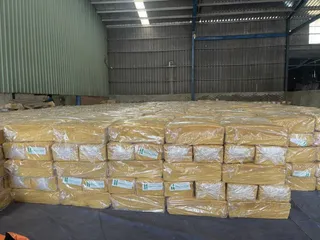 Stacks of packaged yellow-brown material stored inside a warehouse